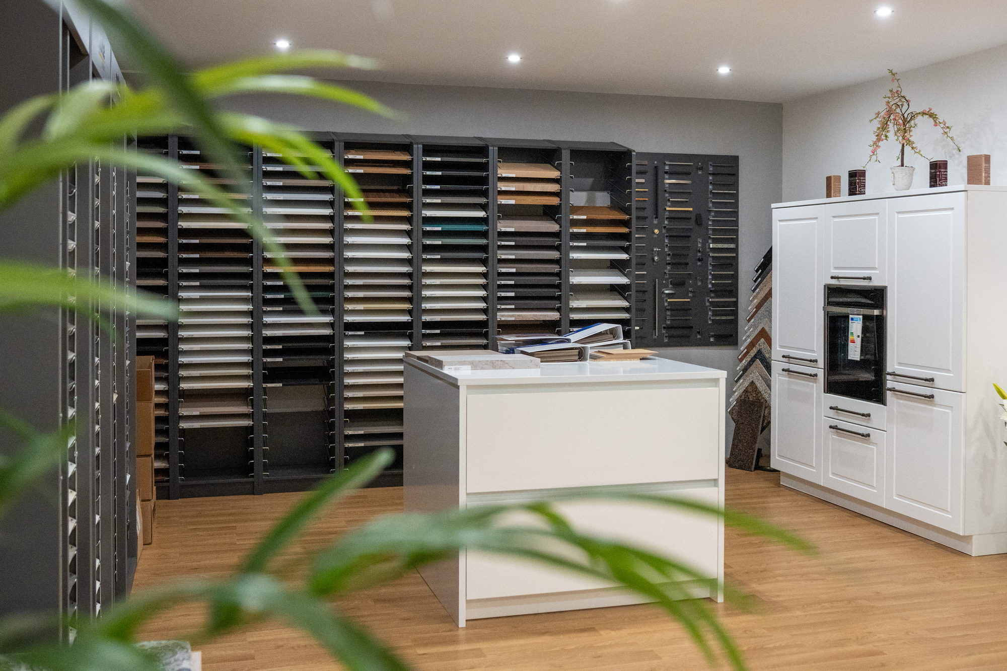 Musterraum mit Fronten- und Dekorwand und weißer Auswahlinsel im Küchenstudio, Küchenplanung für Paderborn